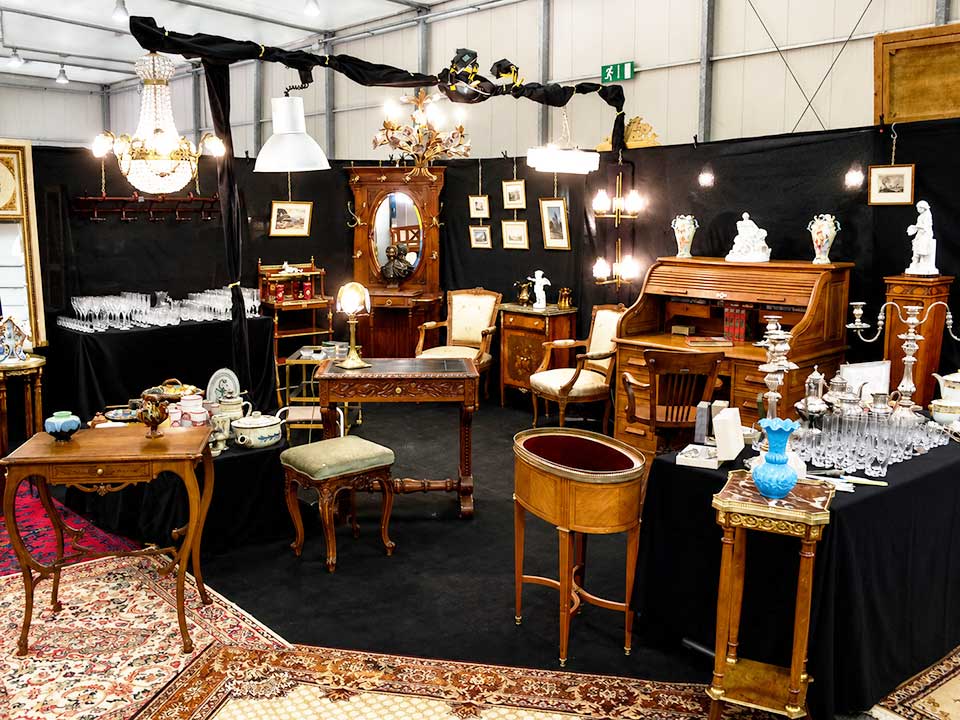 Mobilier ancien, objets d'art, cristal et argenterie présentés dans un stand d'antiquités
