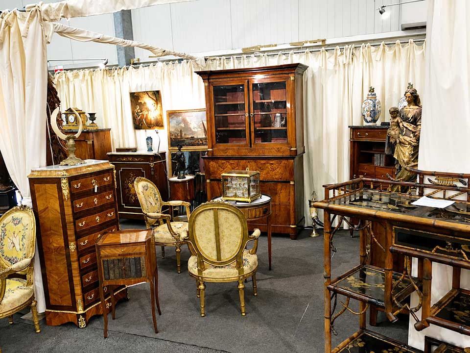 Mobilier ancien, sièges d'époque, commodes marquetées et objets d'art dans un stand d'antiquaire